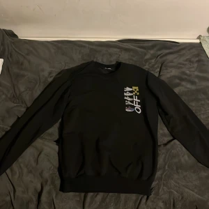 Svart tröja från Off-White - Säljer en svart tröja från Off-White med tryck av olika sneakers och texten 'OFF' på framsidan. Tröjan har långa ärmar och en rund halsringning. Perfekt för dig som gillar streetwear och unika designer.