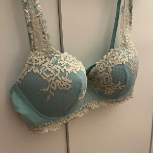 Turkos spets-bh - Säljer en vacker turkos bh med vita spetsdetaljer. Bh:n har vadderade kupor och justerbara axelband. Perfekt för att känna sig extra fin till vardags eller speciella tillfällen. Bh:n är ifrån Intimissmi! Säljer pga att den är för liten!