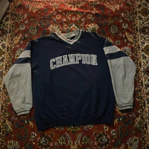 Blå och grå sweatshirt från Champion - Säljer en snygg blå sweatshirt från Champion. En liten skråma precis över P i Champion loggan, annars inga fel alls
