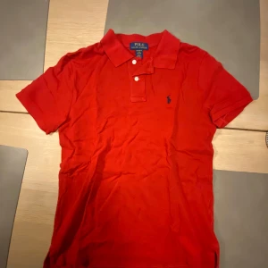 Röd pikétröja från Ralph Lauren - Säljer en klassisk röd pikétröja från Ralph Lauren med korta ärmar och knappar vid kragen. Storlek på sista bilden, helt oanvänd. kan hämtas i Skövde eller fraktas! Mvh Lukas.
