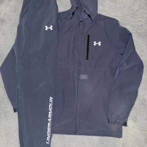 Blå tracksuit från Under Armour.  - Blå under armour dress. Jackan är storlek M och byxorna är storlek S men passar perfekt för dom som har M. Helt ny, prislapparna och kvittot finns 