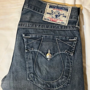 Blå jeans från True Religion - Snygga blå jeans från True Religion med unika bakfickor och kontrastsömmar. De har en straight passform och klassisk femficksdesign. Låg midja 