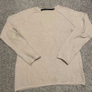 Knitted Sweatshirt - Säljer en stilren beige stickad tröja från lager 157. Tröjan har en enkel design med långa ärmar och en rund halsringning. Tröjan är sällan använd och skicket är 10/10. Perfekt för en avslappnad och bekväm stil.