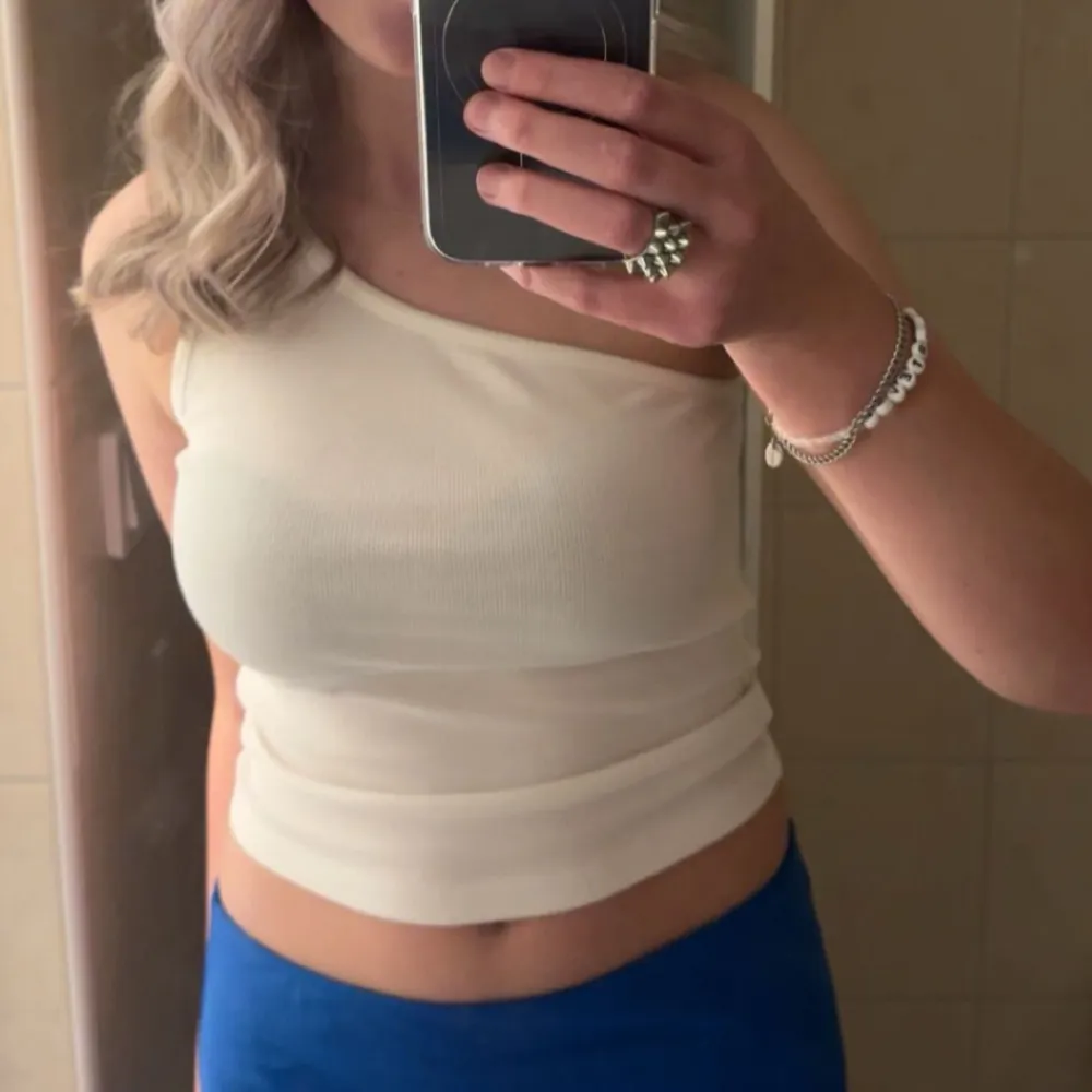 SĂ€ljer en stilren vit oneshoulder topp med ribbad textur đ. Köparen stĂ„r för frakten! âïž. YlĂ€osat.