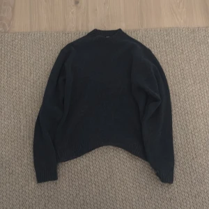 Mörkblå tröja från Uniqlo - Säljer en stilren mörkblå tröja från Uniqlo. Tröjan har en klassisk design med långa ärmar och ribbstickade muddar vid ärmslut och nederkant. Perfekt för kyligare dagar.