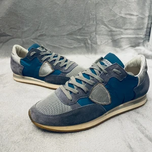 Grå och blå sneakers  Philippe Model TRPX - Snygga sneakers från Philippe Model i en kombination av grått och blått. Skorna har en klassisk design med snörning och en bekväm sula. Tillverkade i en mix av mocka och syntetmaterial, vilket ger en stilren look.😁 Öppen för pris förslag 👍