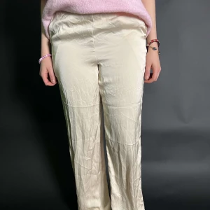 Beige byxor - Snygga beige byxor med en rak passform. Perfekta för en stilren look. De är högmidjade och har en klassisk design som passar till många olika tillfällen. Byxorna är lite noppiga! 