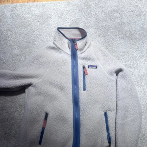 Vit fleecejacka från Patagonia - Hej! Säljer en vit/beige fleece i storlek S, köpt i original butik (Patagonia). Tröjan är nästintill inte använd, utan endast använd ett fåtal gånger.