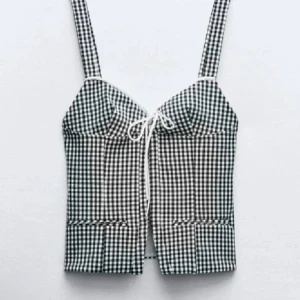Zara topp - Snygg rutig korsett i svart och vit med knytband framtill. Toppen har breda axelband och en figurnära passform som ger en stilren look. Perfekt för varma dagar.