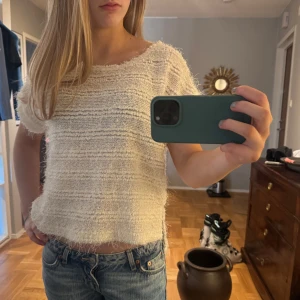 Vit stickad topp - Säljer en vit stickad topp med korta ärmar. Den har en texturerad yta och en avslappnad passform. Perfekt för en stilren och bekväm look.