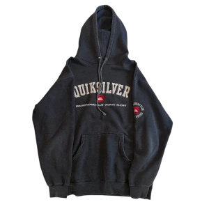 Hoodie från Quiksilver - Säljer en mörk grå hoodie från Quiksilver med tryck på framsidan och ärmen. Den är i bra skick coh har en riktigt cool passform