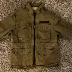 Helt ny Zadig & Voltaire jacka - Säljer en sprillans ny olivgrön jacka från Zadig & Voltaire i storlek XS men passar mer som S-M med dragkedja och flera fickor framtill. Jackan har en militärinspirerad design och en klassisk krage. Perfekt för en avslappnad stil. Alla slitningar är fabriksgjorda. Ny pris ligger på minst 4000! Priset går att diskuteras, skriv vid eventuella funderingar.