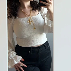 Vit smockad blus - Säljer en stilren vit blus med smockad design och långa ärmar. Blusen har en åtsittande passform upptill och vida ärmar som ger en elegant look. Perfekt för att klä upp eller ner beroende på tillfälle.