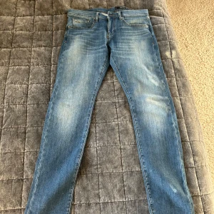 Blå jeans från Armani Exchange - Snygga blå jeans från Armani Exchange med klassisk femficksdesign och dragkedja. Perfekta för en stilren look. De är i en slim model. Jeansen är nästan inte använda alls. Nypris = Runt 2000kr