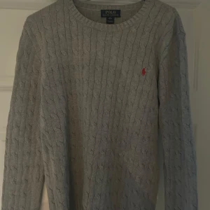 Grå stickad tröja från Ralph Lauren - Säljer en stilren grå stickad tröja från Ralph Lauren med det klassiska broderade logotypen på bröstet. Strl Xl kids så typ S vanlig.