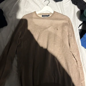 Beige tröja från Polo Ralph Lauren - Säljer en stilren beige tröja från Polo Ralph Lauren i Pima bomull. Tröjan har en klassisk design med rund hals och det ikoniska logotypbroderiet på bröstet. Perfekt för en avslappnad men elegant look. Den är även aldrig använd för jag råkade köpa fel storlek och det där dreglar jag säljer den. Priset kan diskuteras vid en snabb affär 