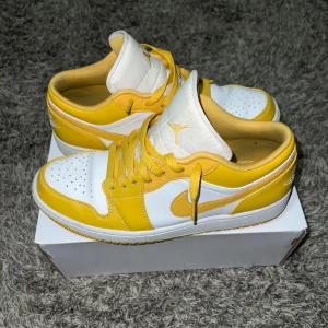  Nike Air Jordans - Snygga Nike Air Jordans i en fräsch gul och vit färgkombination. Skorna har klassisk snörning och en ikonisk design med det välkända Jordan-märket på plösen. Perfekta för att ge din outfit en färgklick.