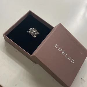 Silverfärgad ring från Edblad - Snygg och unik silverfärgad ring från Edblad med ett coolt, geometriskt mönster. Perfekt för att ge en edgy touch till din stil. Kommer i originalförpackning. Den är stål fri som gör att du kan duscha i den exempel och den inte råstar och byter färg. Hämta gärna vi bestämd plats.
