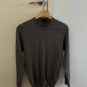 Grå tröja från Oscar Jacobson - Säljer en stilren grå tröja från Oscar Jacobson. Tröjan är långärmad och har en klassisk rund halsringning. Perfekt för både vardag och mer uppklädda tillfällen.