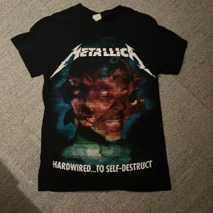 Svart Metallica t-shirt - Svart t-shirt från Gildan med Metallica-tryck. Framsidan har ett färgstarkt motiv och texten 'Hardwired...To Self-Destruct'. Baksidan pryds av texten 'In the name of desperation, in the name of wretched pain'