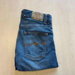 Nudie Jeans - Snygga blå jeans från Nudie Jeans med klassisk femficksdesign och en diskret logga på bakfickan. Jeansen har en slim passform och är perfekta för en avslappnad stil. De är tillverkade i högkvalitativt denim och har en bekväm midwaist.
