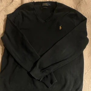 Svart tröja från Ralph Lauren - Säljer en klassisk svart tröja från Ralph Lauren i mjuk Pima bomull. Tröjan har en v-ringad design och det ikoniska broderade logotypen på bröstet. Kan ordna mer bilder om efterfrågas 👍