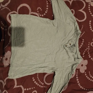 Grå långärmad tröja med knappar - Säljer en stilren grå långärmad tröja med knappdetaljer vid halsen. Perfekt för en avslappnad look.
