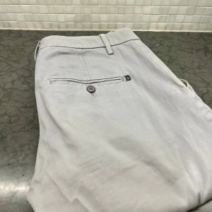 Dondup chinos - Snygga grå chinos med diskret randigt mönster. De har en klassisk design med knappar och hällor för bälte. Perfekta för en stilren look. Dondup shinos nypris 3500kr 