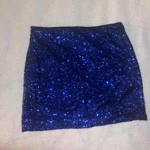 Blå glittrig kjol — Bik Bok - Snygg blå kortkjol med glittriga paljetter som ger en festlig look. Perfekt för att sticka ut på festen. Kjolen har en tight passform som framhäver figuren.