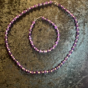 Lila ametist halsband och armband - Elegant set med facetterade lila ametistpärlor. Halsbandet och armbandet har silverlås som ger en fin kontrast till de djupa lila tonerna. Perfekt för att lägga till en touch av färg och elegans till din stil.