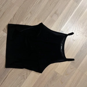 Svart ribbad linnetopp från Bik Bok - Snygg svart ribbad linnetopp från Bik Bok. Den har smala axelband och en stilren design.