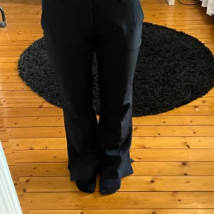 Svarta kostymbyxor petite - Snygga svarta kostymbyxor med bootcut-stil. Byxorna har låg midja och en elegant passform. Slits vid foten. 