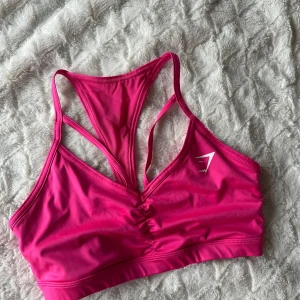 GS Power sportsbra - Snygg rosa sportbh från Gymshark med brottarrygg och liten logga på bröstet. Stretchig och mjuk material. Storlek M. 