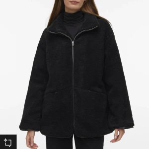 Svart teddyjacka med dragkedja Vero Moda - Mysig svart teddyjacka med dragkedja framtill. Jackan har en avslappnad passform och långa ärmar, perfekt för kyliga dagar.