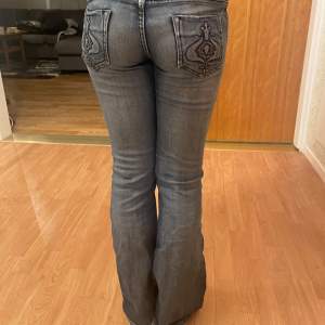 Säljer ett par snygga blå/gråa  bootcut jeans med coola broderade detaljer på bakfickorna. De är lågmidjade! Storlek xs men passar mig som har s 