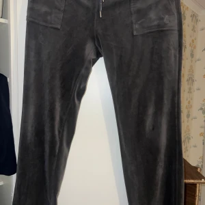 Svarta byxor från Juicy Couture - Säljer ett par snygga mörkgrå byxor från Juicy Couture i storlek XL. Köpta från Nelly och använda snart i ett år. Dem har något litet vitt på snörena som varit där sen jag fick dom ( säljer dom för att jag inte använder dom lika mycket längre )