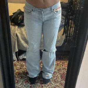 lågmidjad bootcut jeans - asballa ljusblåa lågmidjade jeans med hål   midjemått: 39cm  innerben: 82cm