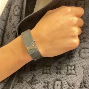 Louis Vuitton armband - Svart armband från Louis Vuitton med det ikoniska LV-emblemet i silver. Armbandet har en elegant design med präglade detaljer och är perfekt för att ge en lyxig touch till din stil. Pris kan diskuteras. Inga repor eller skador