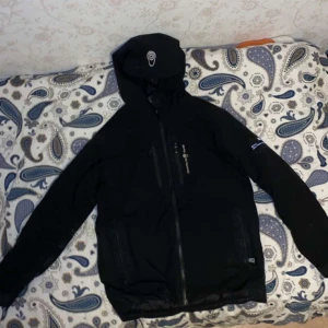 Svart jacka från Sail Racing - Snygg svart jacka från Sail Racing med broderad logga och dragkedja. Perfekt för kyliga dagar med sin stilrena design och funktionella detaljer. Sail racing, köptes för 5 månader sen och är använd få gånger då den blev för liten. Pris går att diskutera 