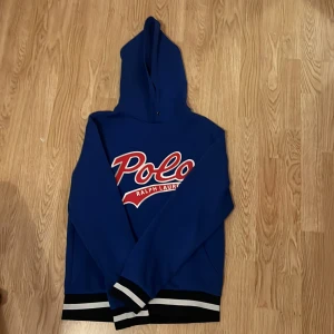 Ralph Lauren - Snygg blå hoodie från Ralph Lauren storlek S. Passar perfekt på någon som är runt 174-177cm lång. Det är en ralph lauren hoodie med stor Polo-logga i rött och silver på framsidan. Den har en klassisk huva och ribbade muddar i svart och vitt vid ärmslut och nederkant. Perfekt för en avslappnad stil. Kontakta för fler frågor🤩🤩🤩