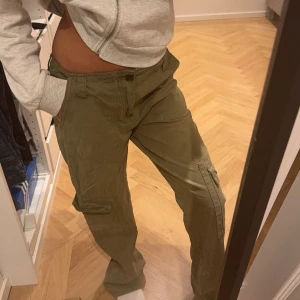 Gröna cargobyxor - Snygga gröna cargobyxor med flera fickor och en avslappnad passform. Perfekta för en casual look. Byxorna har en låg midja.