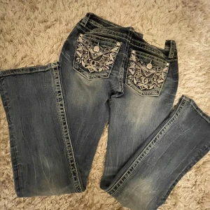 Miss me jeans - Sjukt snygga knappt använda miss me jeans med unika broderade detaljer på bakfickorna. De har en bootcut-stil och är perfekta för en avslappnad look. Jeansen har en klassisk femficksdesign och knappar framtill.