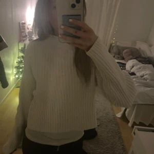 Vit ribbad stickad tröja - Mysig vit stickad tröja med ribbad struktur. Tröjan har en mellan krage och långa ärmar, perfekt för kyliga dagar. Den är något croppad och ger en stilren look. Storlek 13-14 men sitter som en xs