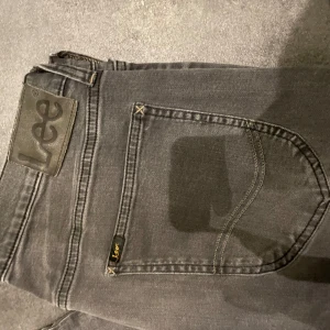 Lee jeans  - Säljer ett par grå jeans från Lee. Bra skick utöver de lilla hålet på sidan av benet. Size 30/32.
