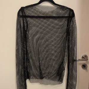 Svart nättröja från Amisu - Snygg svart nättröja från Amisu i storlek S. Perfekt för nyår eller för att lägga till en edgy touch till din outfit. Tröjan har långa ärmar och är tillverkad i ett transparent nätmaterial.