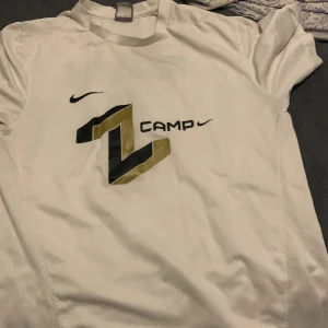 Vit fotbollströja från Nike - Säljer en vit kortärmad fotbollströja från Nike med trycket 'Z Camp' och 'Ibrahimović 8' på ryggen. Tröjan har en stilren design med Nike-logga och är tillverkad i ett lätt och andningsbart material.