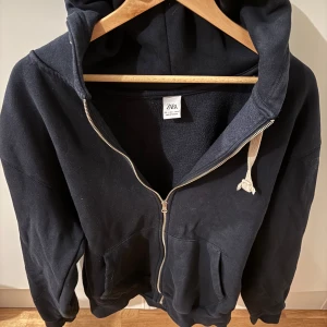 Marinblå zip hoodie från Zara - Säljer en marinablå zip hoodie från Zara med dragkedja och huva. Perfekt för en avslappnad stil. Den har fickor framtill och är tillverkad i ett mjukt material. Inköpt på herravdelningen men kan användas av tjejer med därav unisex. Tröjan är i bra skick trots att den varit använd ganska ofta.