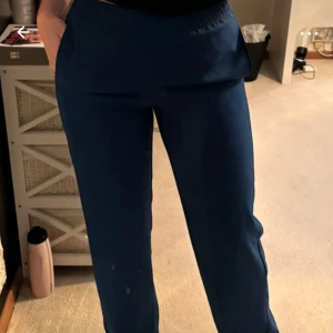 Blå byxor från J.XX - Snygga blå byxor från J.XX med elastisk midja för extra komfort. Perfekta för en avslappnad stil med en loose passform. Byxorna har en enkel design som gör dem lätta att matcha med olika toppar.