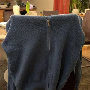 Blå stickad tröja med dragkedja - Säljer en snygg blå stickad tröja med dragkedja. Perfekt för kyliga dagar och ger en stilren look. Tröjan har en enkel design som passar till det mesta. 10/10 i skick inte använd pga för liten 