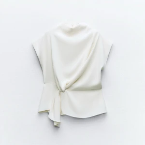 Vit omlottopp - Elegant vit omlottopp med ”knytning” i midjan. Toppen har en hög krage och är ärmlös, vilket ger en stilren och modern look. Använd 1 gång, perfekt nu till nyår ✨✨